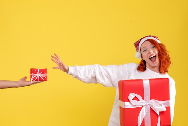 Free photo front view of young woman holding xmas present on yellow wall