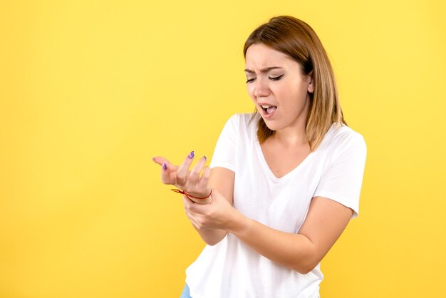 Front view of young woman hurt her arm on yellow wall