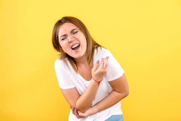 Front view of young woman hurt her arm on yellow wall