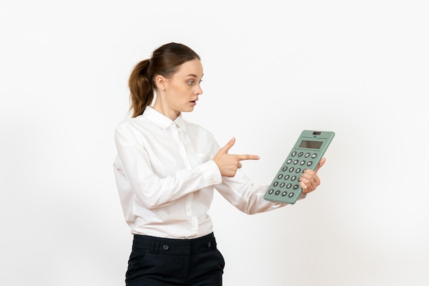 Бесплатное фото Вид спереди молодая женщина в белой блузке, держащая огромный калькулятор на белом фоне, женские эмоции, чувство офисной работы