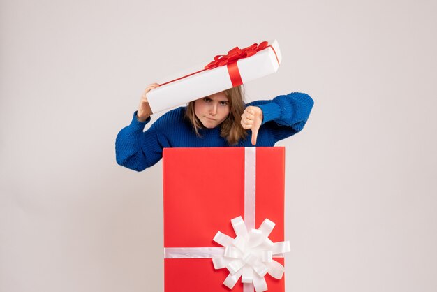 Front view of young woman inside present box displeased on white wall