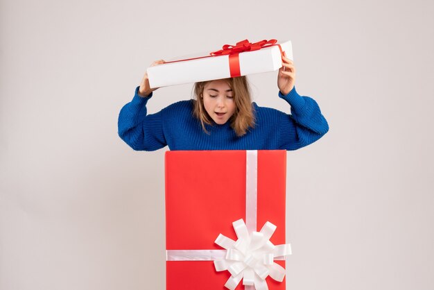 Front view of young woman inside present box on white wall