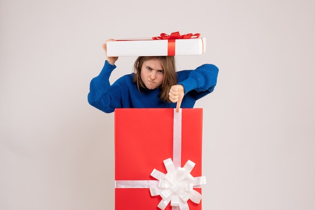 Front view of young woman inside present box on white wall