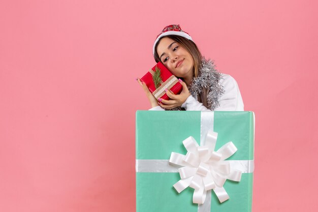 Front view of young woman inside present holding another present on pink wall