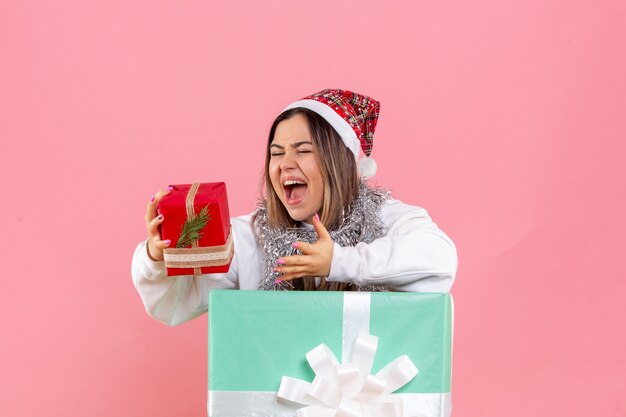 Front view of young woman inside present holding another present on pink wall