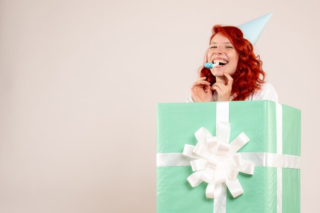 白い背景の上のキャップとプレゼントの中の正面図若い女性