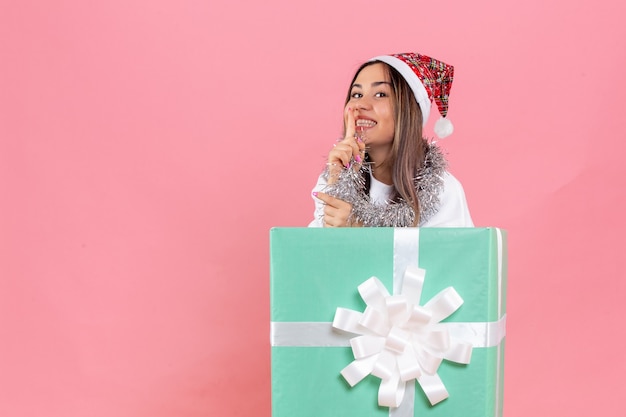 Front view of young woman inside present with garlands on the pink wall