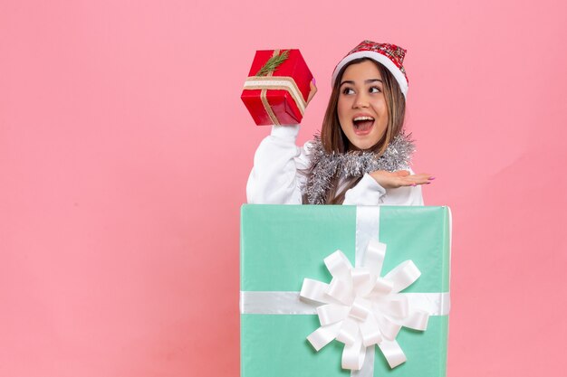 Front view of young woman inside present with garlands on the pink wall