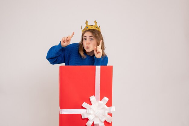 Front view of young woman inside red present box on white wall