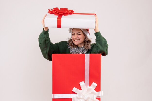 白い壁の上の赤いプレゼントボックス内の若い女性の正面図