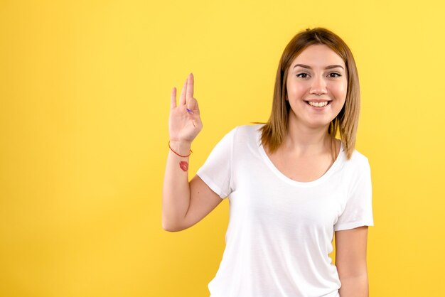 Front view of young woman just smiling on yellow wall