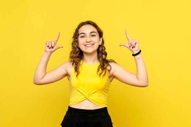 Front view of young woman just smiling on yellow wall