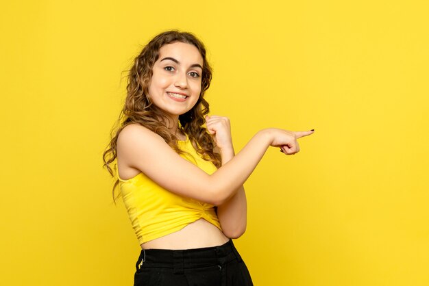 黄色の壁に微笑んでいる若い女性の正面図