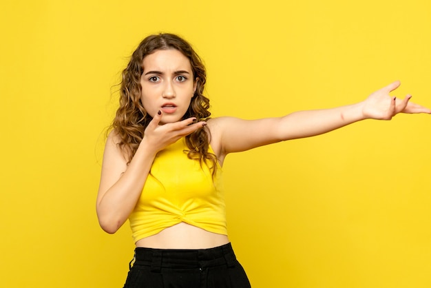 Front view of young woman just standing on yellow wall