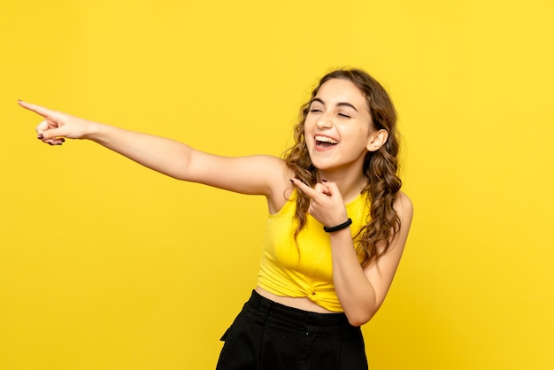 Вид спереди молодой женщины, смеющейся на желтой стене