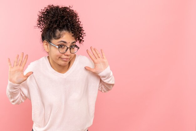 Front view of young woman on light pink wall