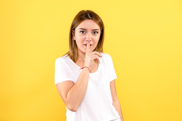 Front view of young woman on light yellow wall