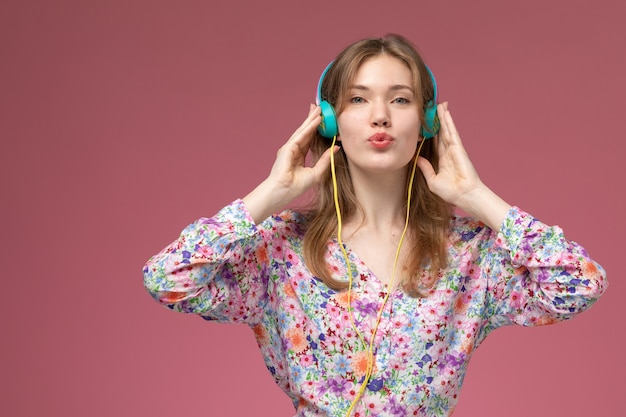 Front view young woman listening to song and holding headphone closer to herself