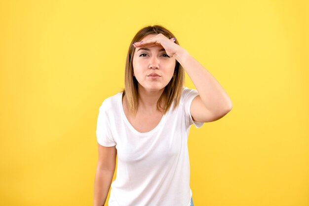 Front view of young woman looking at distance on yellow wall