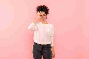 Free photo front view of young woman looking through fingers on pink wall