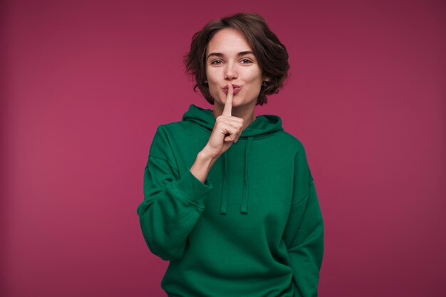 Front view of a young woman making the quiet sign