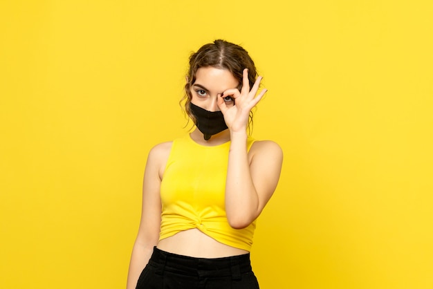黄色い床パンデミックcovid感情ウイルスのマスクで若い女性の正面図