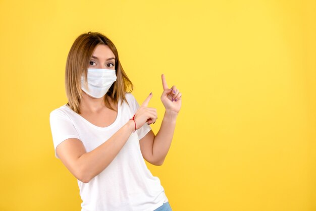 Front view of young woman in mask on yellow wall