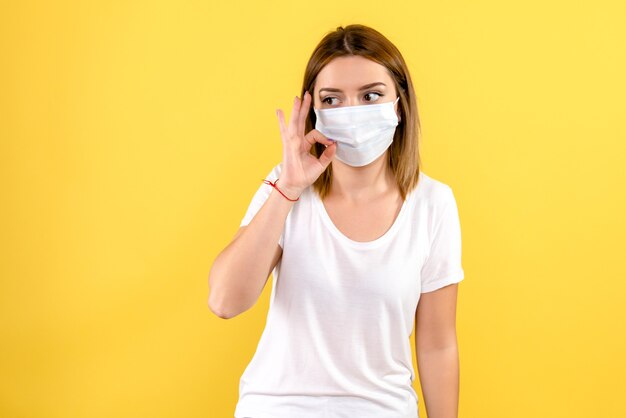 Front view of young woman in mask on yellow wall