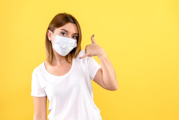 Front view of young woman in mask on yellow wall