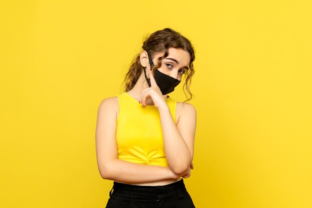 Вид спереди молодой женщины в маске на желтой стене
