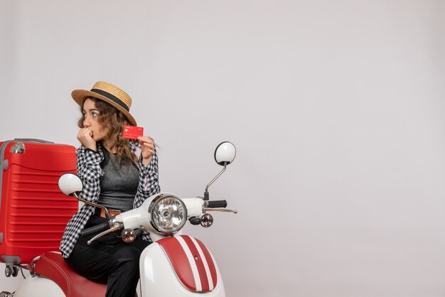 Front view young woman on moped holding card looking at left