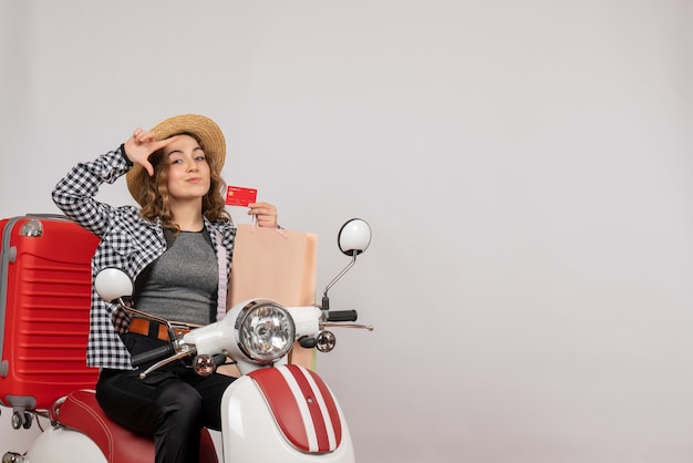 Front view young woman on moped holding card and shopping bag