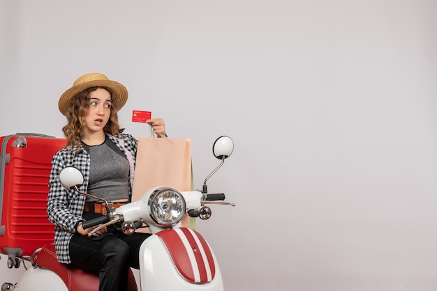 Front view young woman on moped holding up card