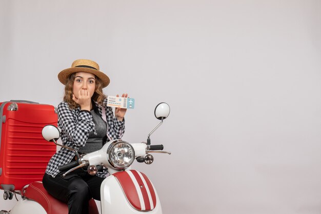 Front view young woman on moped holding up travel ticket