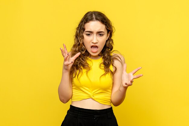 Front view of young woman nervous on yellow wall