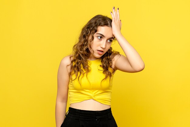 Front view of young woman nervous on yellow wall