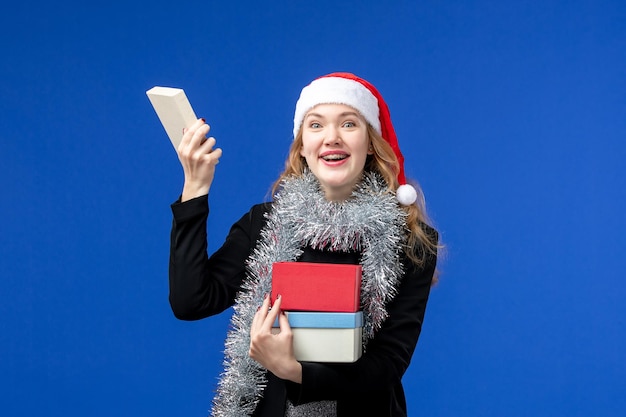 Front view of young woman opening New Year's presents on blue wall