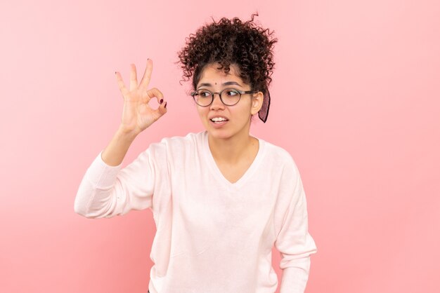 Front view of young woman on pink wall