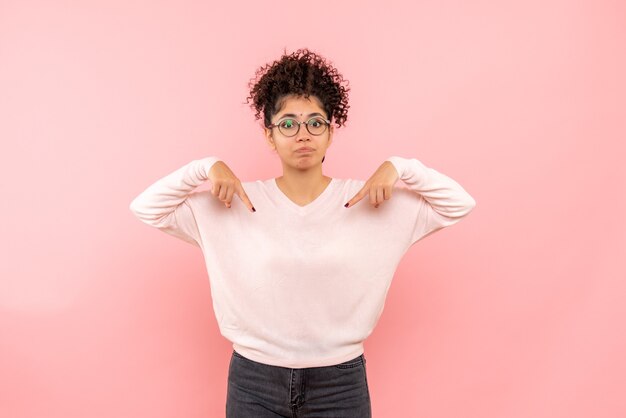 Front view of young woman on pink wall