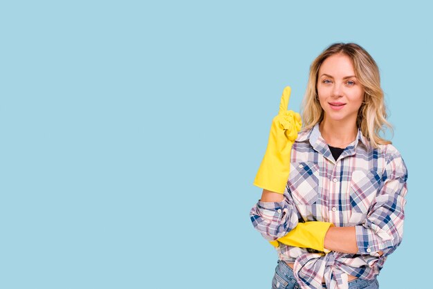 Front view of young woman pointing upwards looking at camera over blue background