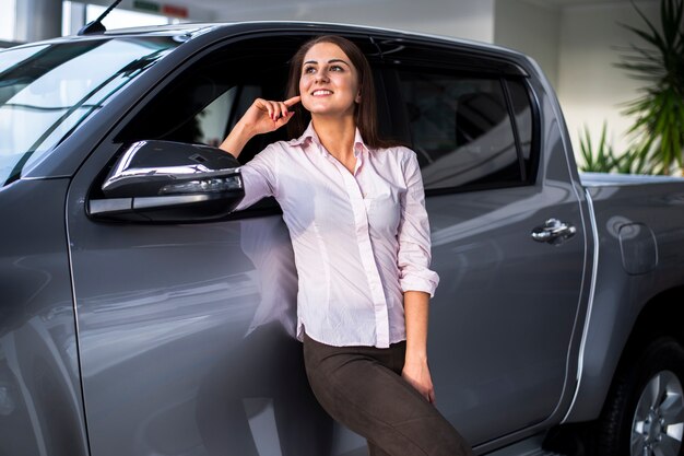 Front view young woman posing next to car