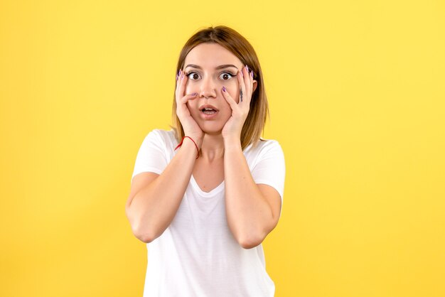 Front view of young woman posing on yellow wall