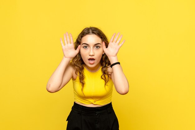 Front view of young woman posing on yellow wall