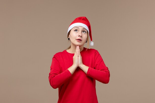 Front view of young woman praying on brown