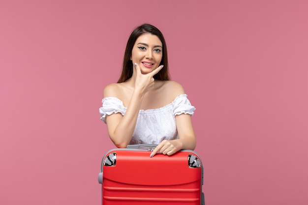 Вид спереди молодая женщина готовится к отпуску со своей красной сумкой на розовом столе, путешествие на море, женщина за границей, отдых