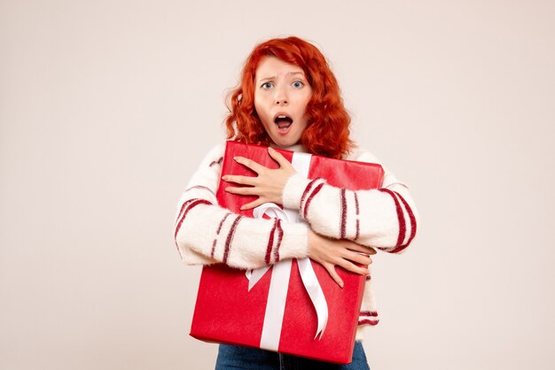 Front view of young woman protecting her big present on white wall