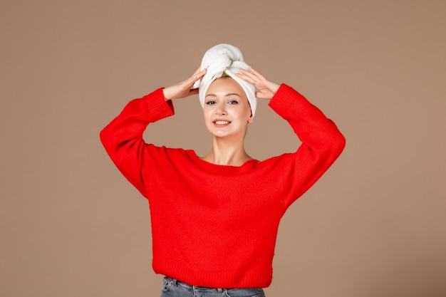 front view of young woman in red shirt with towel on her head on brown wall