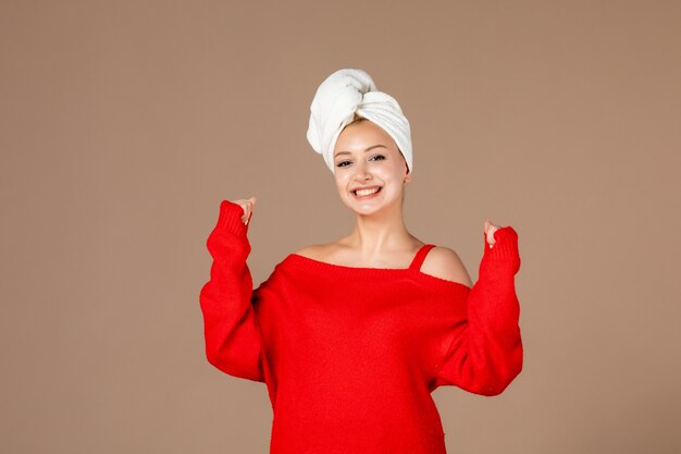 front view of young woman in red shirt with towel on her head on brown wall