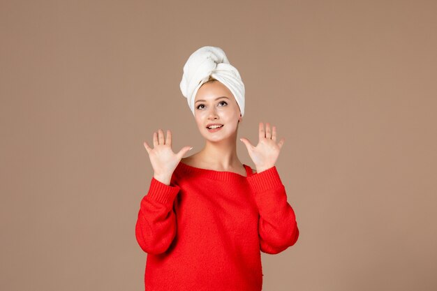 front view of young woman in red shirt with towel on her head brown wall