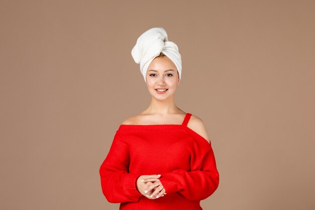 front view of young woman in red shirt with towel on her head brown wall